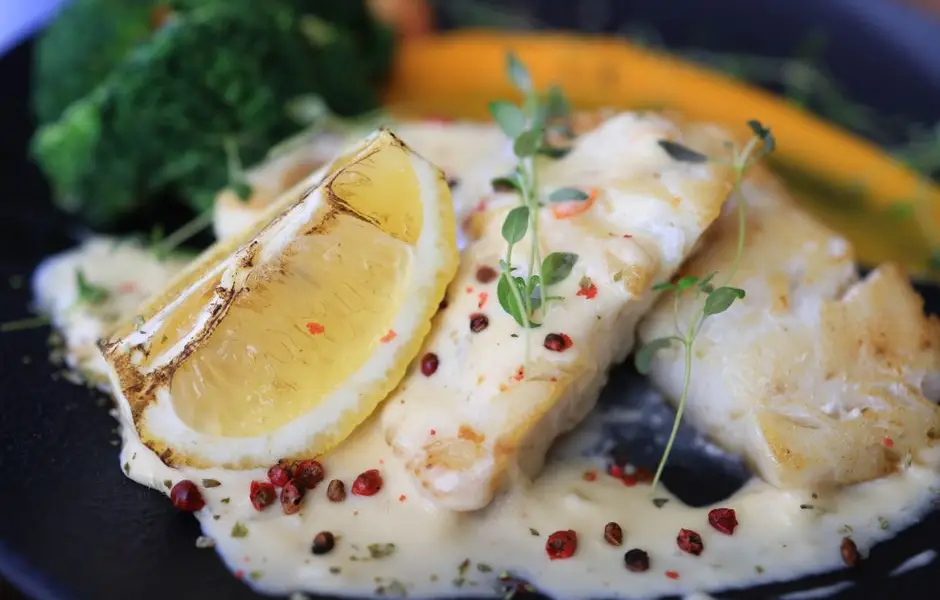 Sauce beurre blanc onctueuse nappant un filet de poisson, échalotes et persil